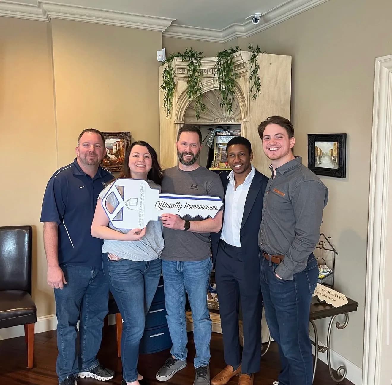 Family of buyers holding an Officially Homeowners sign at closing