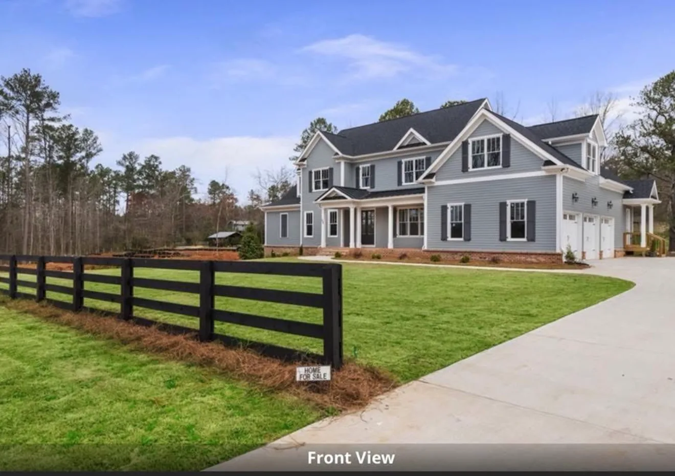 Newly built farmhouse behind black four-board fencing