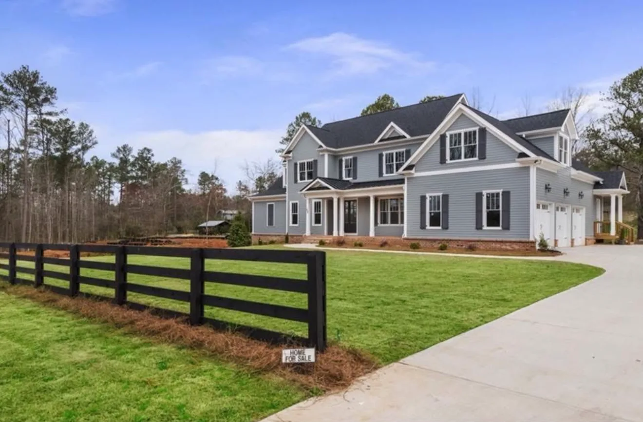 Newly built farmhouse behind black four-board fencing