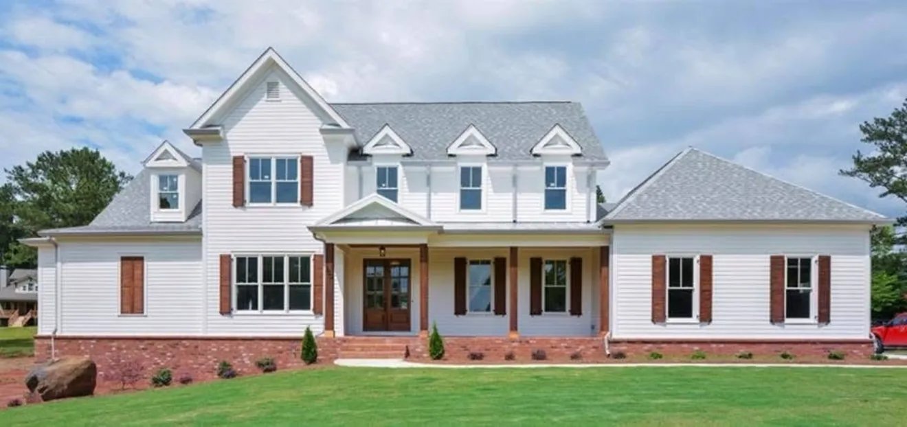 White two-story new build with a covered entry and manicured front lawn